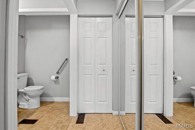 bathroom featuring a closet, toilet, and baseboards