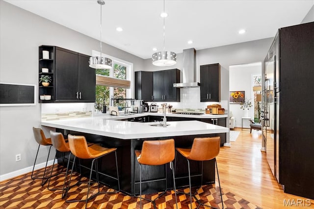 1 W Walinca, Saint Louis, MO 63105 - kitchen with wall chimney exhaust hood, light countertops, dark cabinets, a breakfast bar area, and recessed lighting