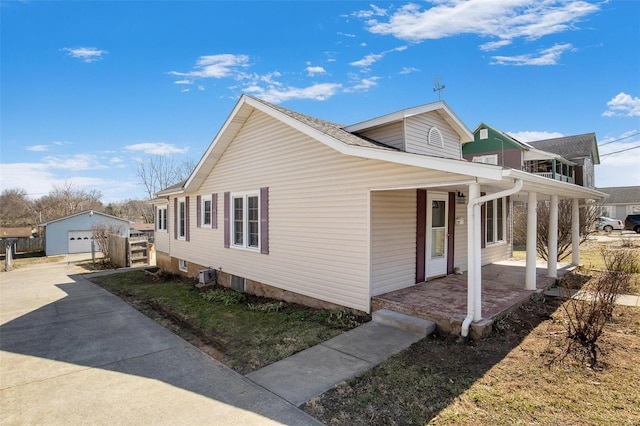 view of home's exterior with covered porch, an outbuilding, a garage, and driveway
