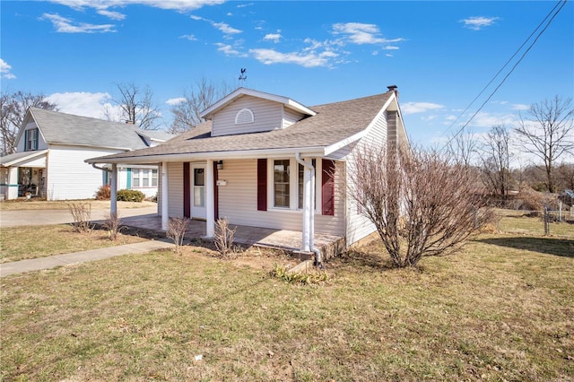 view of front of property with covered porch, a front yard, and roof with shingles