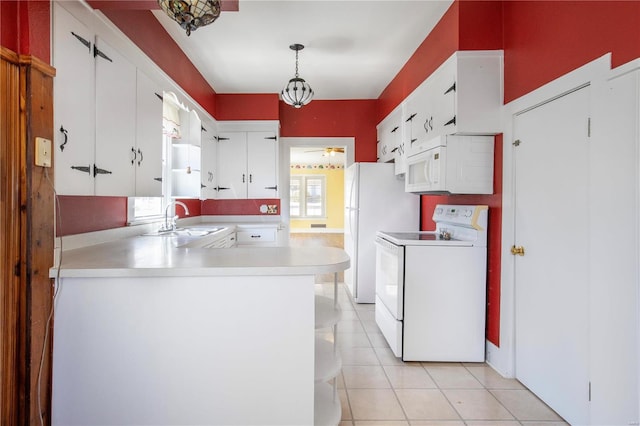 kitchen with white appliances, a sink, ceiling fan, light countertops, and a peninsula
