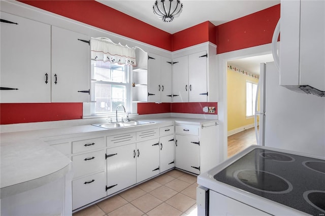 kitchen with electric range, a sink, white cabinetry, freestanding refrigerator, and light countertops