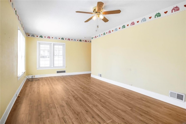 empty room with wood finished floors, baseboards, and a ceiling fan