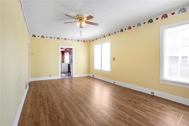 unfurnished room featuring a ceiling fan, wood finished floors, and baseboards