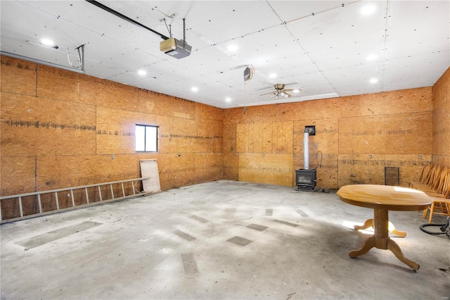 miscellaneous room with unfinished concrete flooring, a wood stove, and a garage