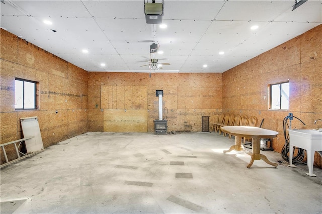 misc room with a wood stove, unfinished concrete floors, ceiling fan, and recessed lighting