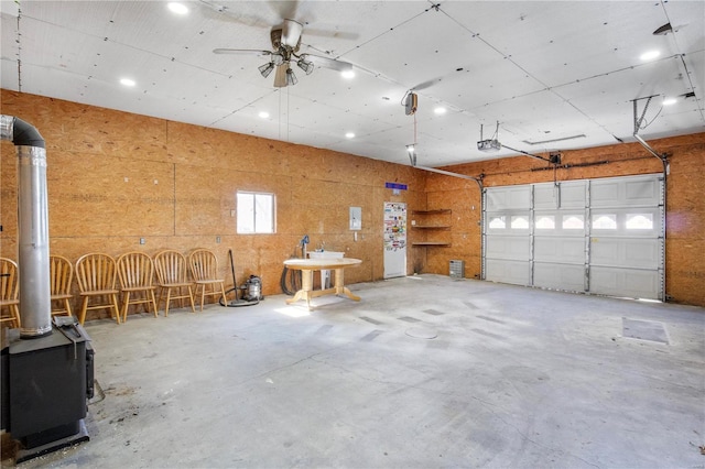 garage with a wood stove, a garage door opener, ceiling fan, and recessed lighting