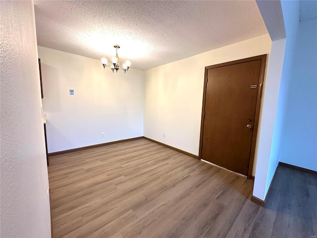 1308 Condo Dr, Rolla, MO 65401 - unfurnished room featuring a chandelier, wood finished floors, baseboards, and a textured ceiling