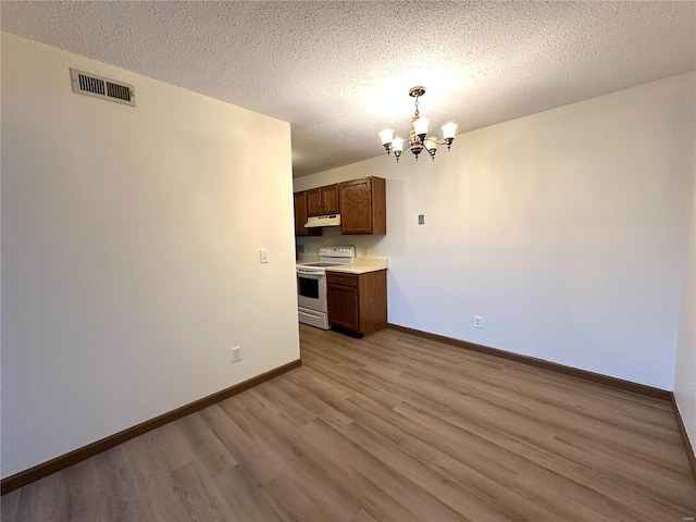 1308 Condo Dr, Rolla, MO 65401 - kitchen with white electric range oven, a chandelier, wood finished floors, under cabinet range hood, and baseboards