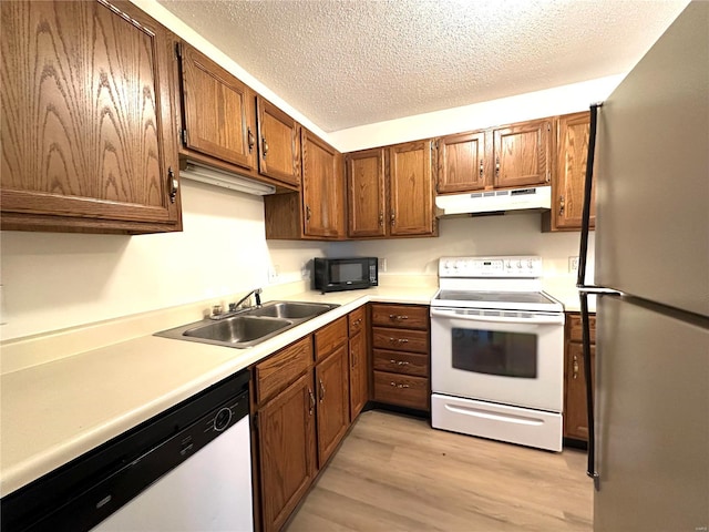 1308 Condo Dr, Rolla, MO 65401 - kitchen with white appliances, under cabinet range hood, a sink, light wood-style floors, and light countertops