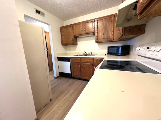 1308 Condo Dr, Rolla, MO 65401 - kitchen featuring white appliances, under cabinet range hood, a sink, light wood-style flooring, and light countertops