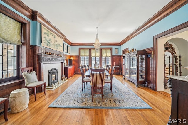 4386 Westminster Pl, Saint Louis, MO 63108 - dining room featuring a chandelier, hardwood / wood-style flooring, arched walkways, ornamental molding, and a glass covered fireplace