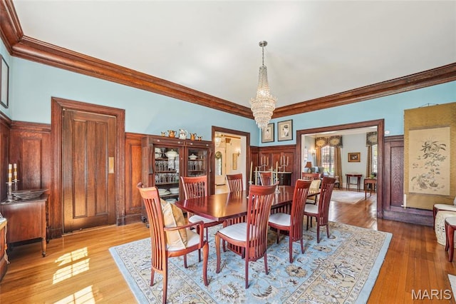 4386 Westminster Pl, Saint Louis, MO 63108 - dining area featuring crown molding, light wood finished floors, and a chandelier