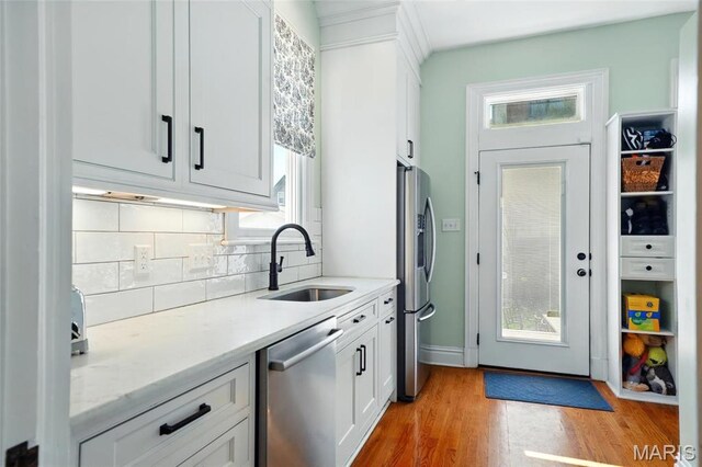 4386 Westminster Pl, Saint Louis, MO 63108 - kitchen with stainless steel appliances, backsplash, light wood finished floors, and plenty of natural light
