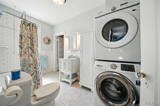 4386 Westminster Pl, Saint Louis, MO 63108 - laundry room with stacked washer and clothes dryer, tile walls, and a wainscoted wall