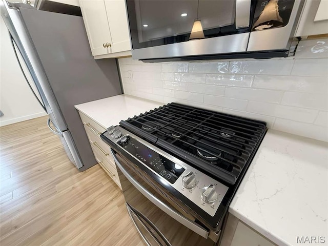 1400 S Jackson St, Salem, MO 65560 - kitchen featuring stainless steel appliances, light wood-style floors, tasteful backsplash, and white cabinetry