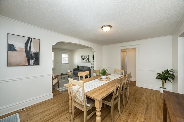 3433 Pine Grove Ave, Saint Louis, MO 63121 - dining area featuring arched walkways, a textured ceiling, light wood-type flooring, ornamental molding, and baseboards
