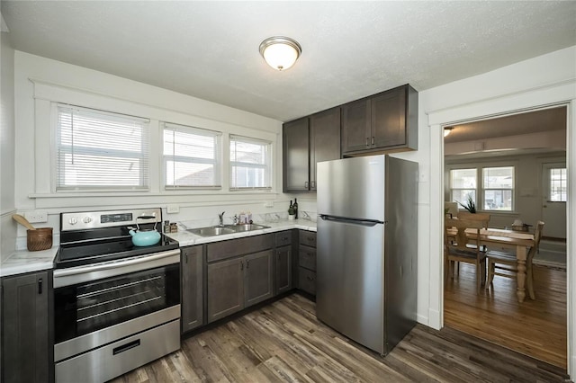 3433 Pine Grove Ave, Saint Louis, MO 63121 - kitchen with stainless steel appliances, a sink, dark wood-style flooring, light countertops, and dark brown cabinetry