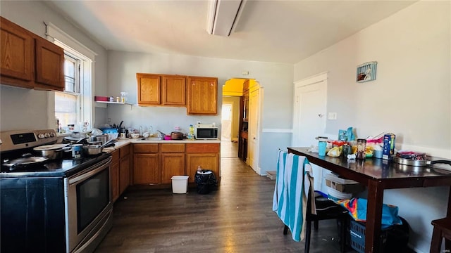 kitchen with stainless steel range with electric stovetop, brown cabinets, dark wood finished floors, and a sink