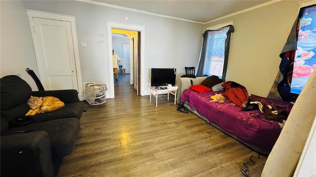 bedroom with crown molding, wood finished floors, and baseboards