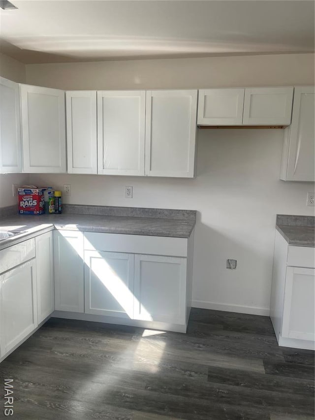 806 E Dover St, Monroe City, MO 63456 - kitchen with dark wood-style flooring, white cabinets, and baseboards