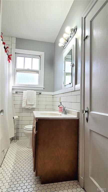 305 Williams St, Washington, MO 63090 - bathroom featuring tile walls, vanity, a shower with shower curtain, and wainscoting