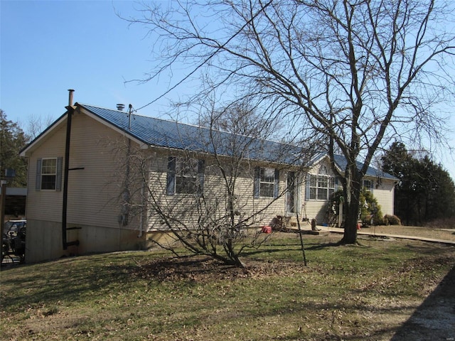 view of side of property featuring a yard and metal roof