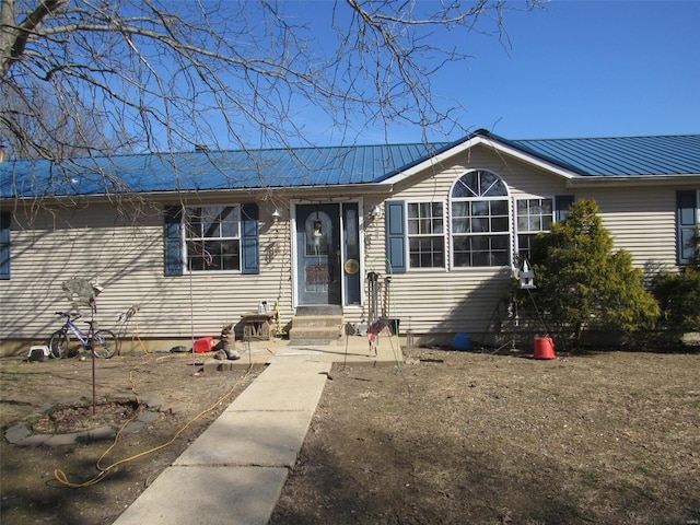 single story home featuring entry steps and metal roof