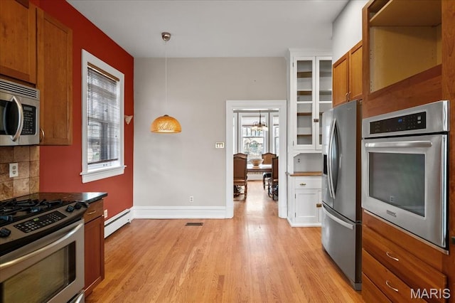 6230 Waterman Ave, Saint Louis, MO 63130 - kitchen featuring stainless steel appliances, a baseboard heating unit, brown cabinetry, glass insert cabinets, and decorative backsplash