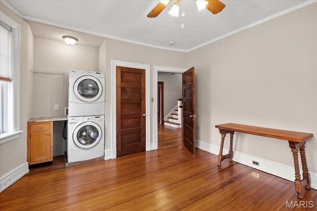 6230 Waterman Ave, Saint Louis, MO 63130 - laundry area featuring stacked washer and clothes dryer, a ceiling fan, cabinet space, light wood-style floors, and ornamental molding