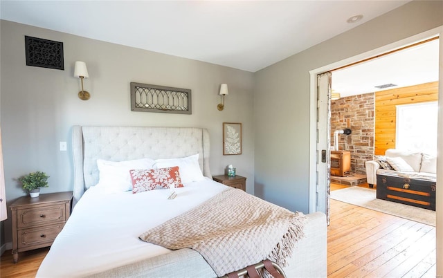 19530 County Road 3620, St James, MO 65559 - bedroom featuring wooden walls, hardwood / wood-style flooring, a wood stove, and an accent wall