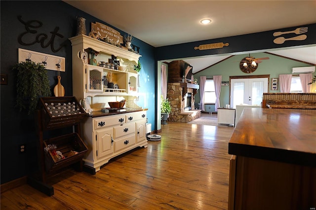 1988 Ripley Route Cc, Doniphan, MO 63935 - kitchen with an AC wall unit, vaulted ceiling, open shelves, hardwood / wood-style floors, and a fireplace
