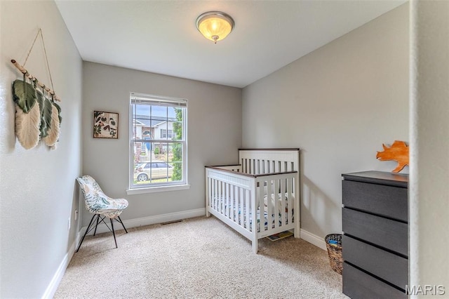 bedroom with carpet flooring, baseboards, and a crib