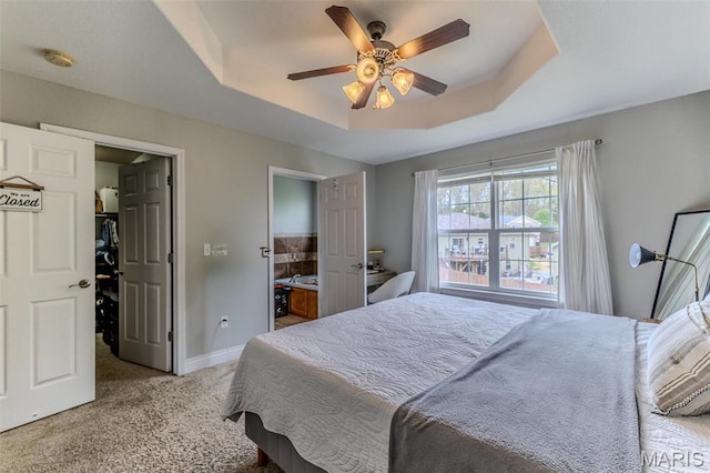bedroom featuring a raised ceiling, carpet, baseboards, and a ceiling fan