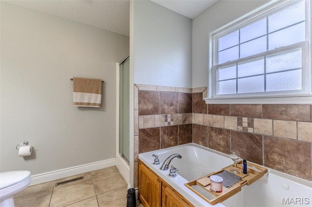 bathroom with tile patterned flooring, toilet, baseboards, a stall shower, and a garden tub