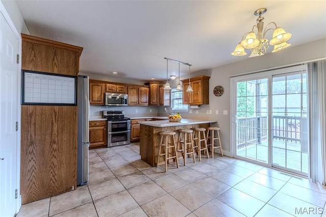 kitchen with stainless steel appliances, brown cabinets, a chandelier, light tile patterned floors, and recessed lighting