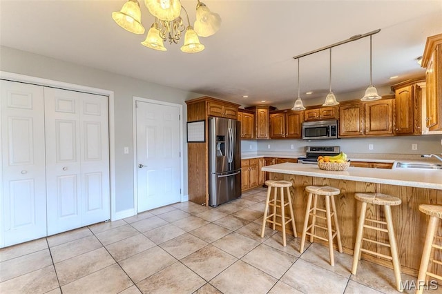kitchen with stainless steel appliances, a sink, light countertops, a chandelier, and a peninsula