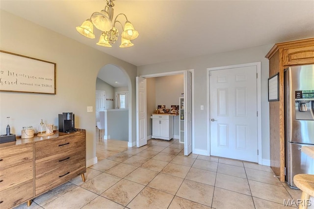 dining area with arched walkways, a chandelier, light tile patterned floors, and baseboards