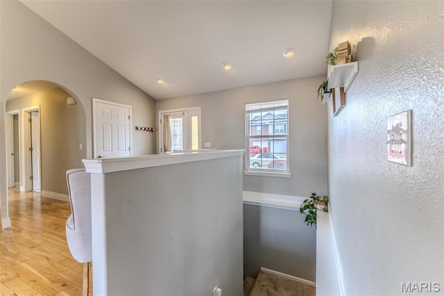 staircase featuring arched walkways, wood finished floors, lofted ceiling, baseboards, and recessed lighting