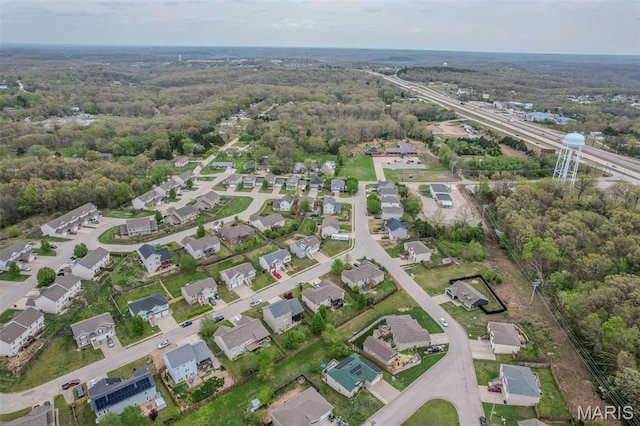aerial view of property and surrounding area with a forest and nearby suburban area