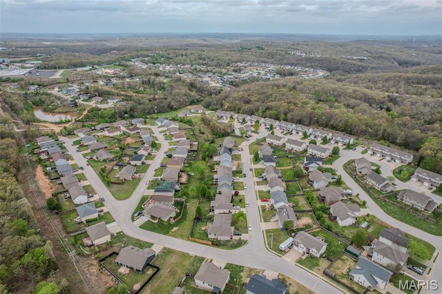 aerial view of property's location featuring nearby suburban area and a heavily wooded area