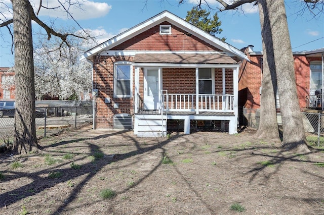 4644 Minnesota Ave, Saint Louis, MO 63111 - shotgun-style home with covered porch, brick siding, fence, and cooling unit