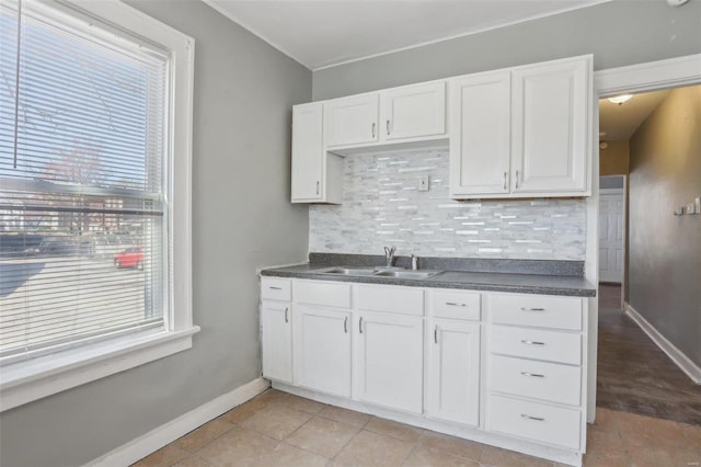 4644 Minnesota Ave, Saint Louis, MO 63111 - kitchen featuring a sink, tasteful backsplash, dark countertops, baseboards, and white cabinetry