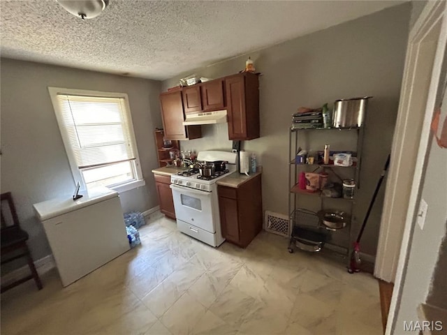 114 Bernhardt Ave, Saint Louis, MO 63121 - kitchen with white gas range, under cabinet range hood, brown cabinets, light countertops, and a textured ceiling