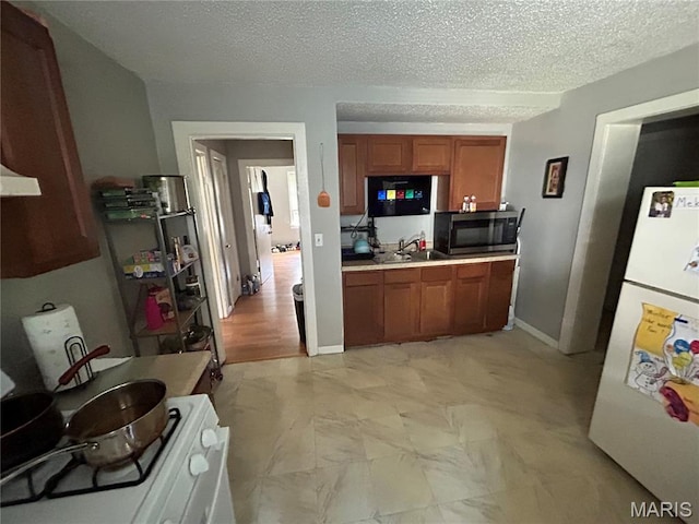 114 Bernhardt Ave, Saint Louis, MO 63121 - kitchen featuring freestanding refrigerator, brown cabinets, stainless steel microwave, stove, and a textured ceiling
