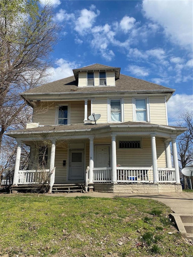 view of front facade with a porch, a front yard, and roof with shingles