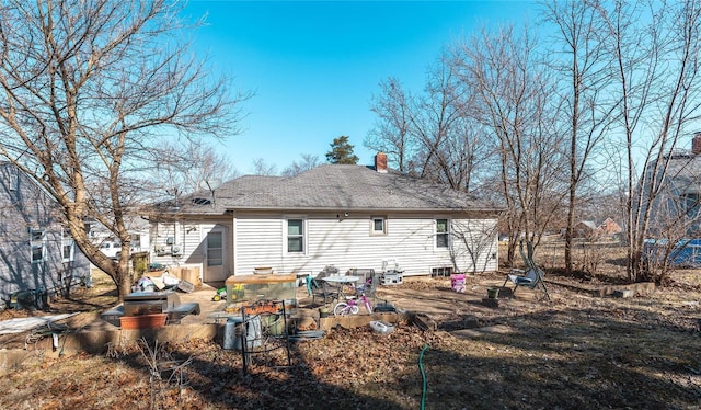 back of house with a chimney, a shingled roof, and a patio area