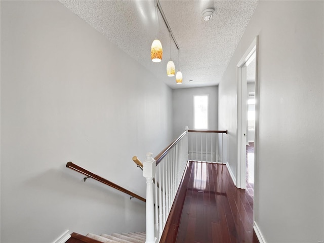 stairway featuring a textured ceiling, wood-type flooring, and baseboards