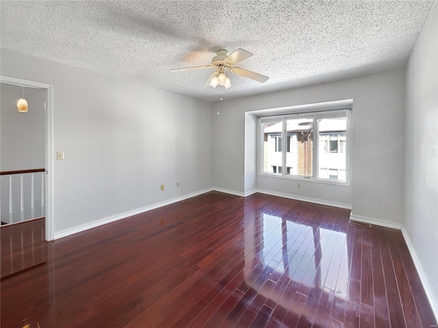 empty room featuring ceiling fan, baseboards, a textured ceiling, and wood finished floors