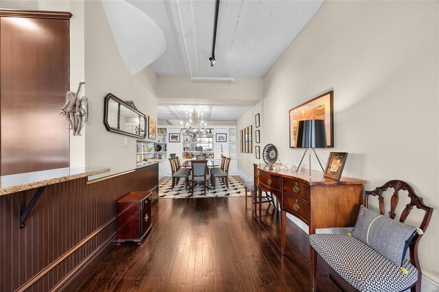 hall featuring dark wood finished floors and a chandelier